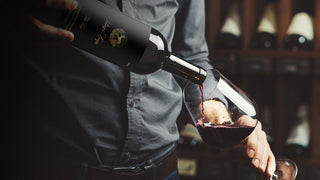 A bottle of Stags' Leap wine, The Leap Cabernet Sauvignon, being poured into a wine glass.