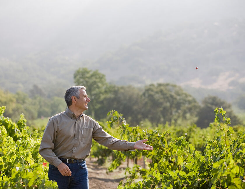 A woman and man walking through the gardens at Stags' Leap with a glass of wine in hand. 